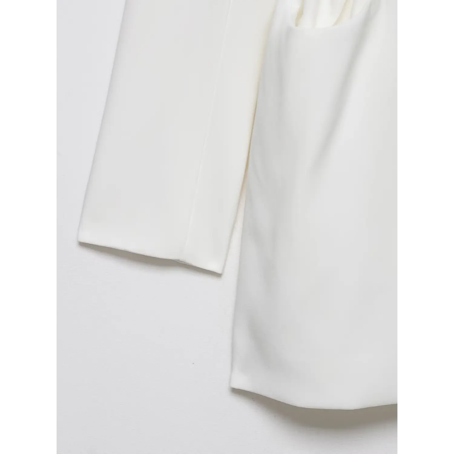 Close up of white blazer dress long sleeve hem and skirt edge, smooth tailored fabric