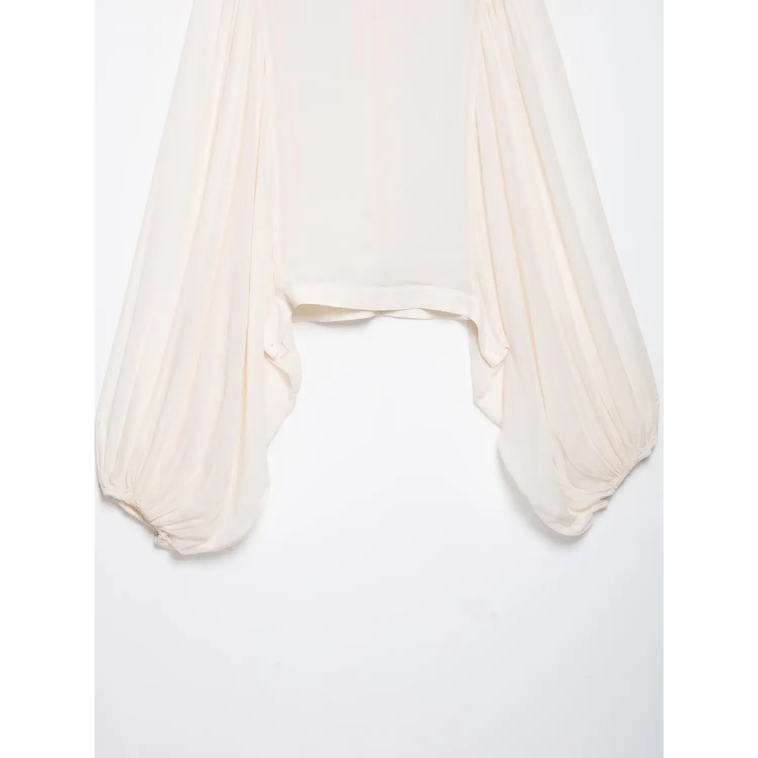 Bottom detail shot of white blouse, oversized bishop puff sleeves and cropped uneven hem