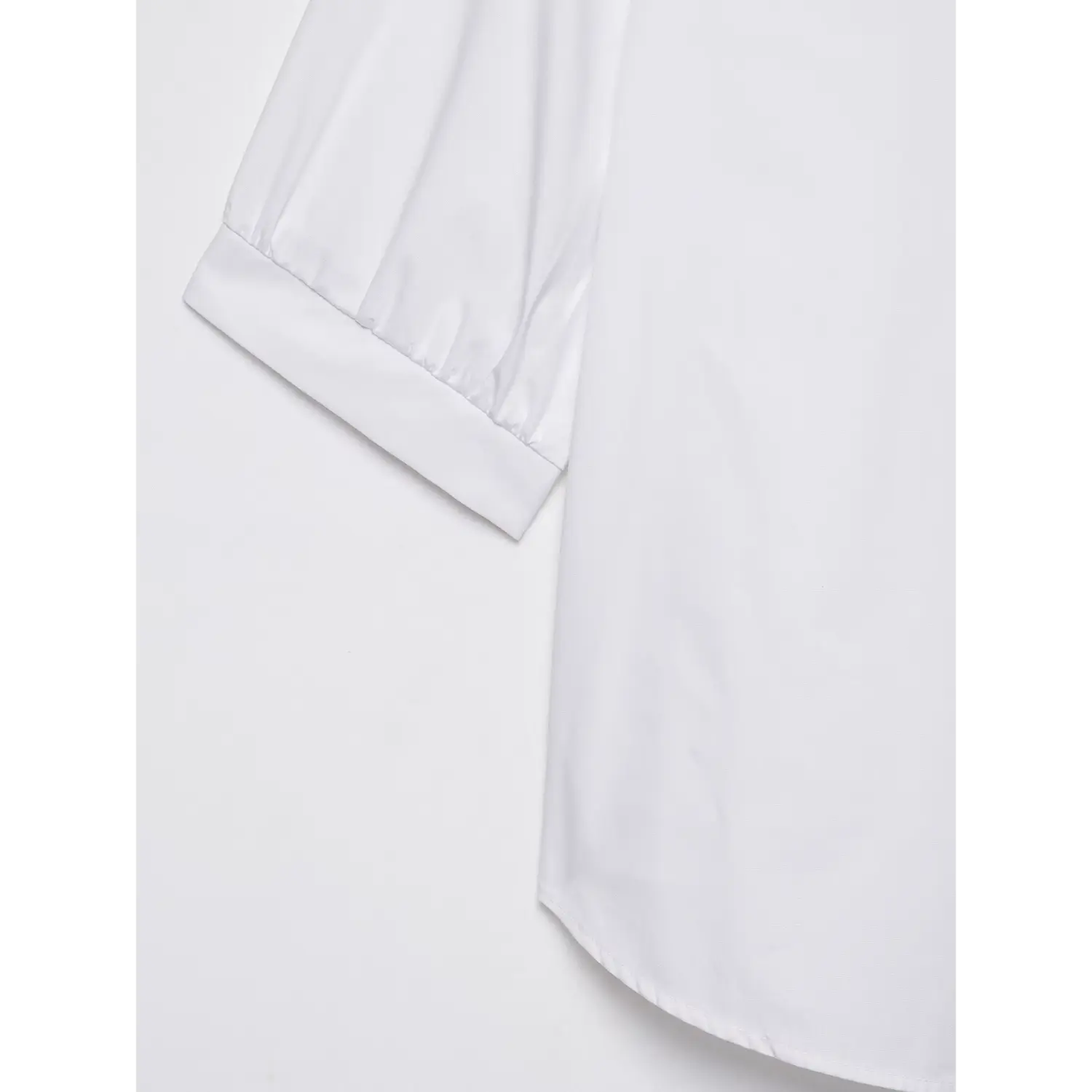 Close-up of puff sleeve cuff and curved hem on white cropped collared shirt