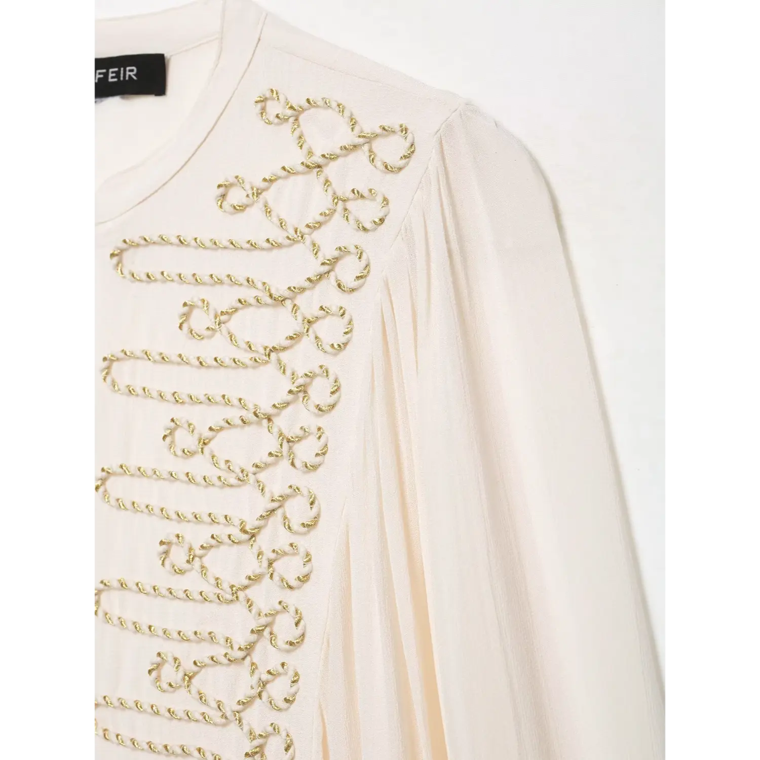 Close‑up of shoulder gold cord embroidery and gathered sleeve on white stand‑collar blouse