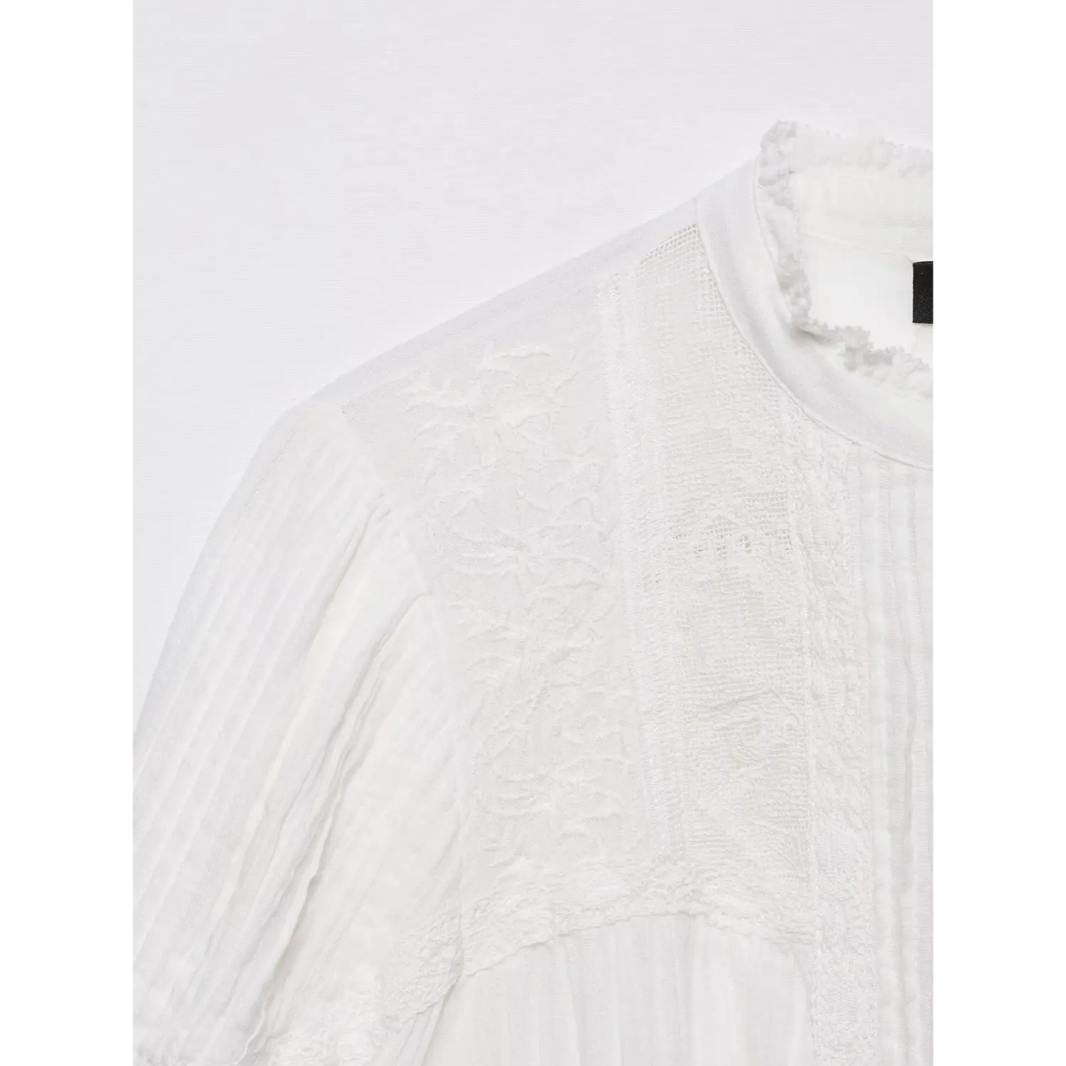 Partial close-up of shoulder and chest panel, sheer mesh fabric with floral embroidery and delicate lace splicing on white vintage shirt