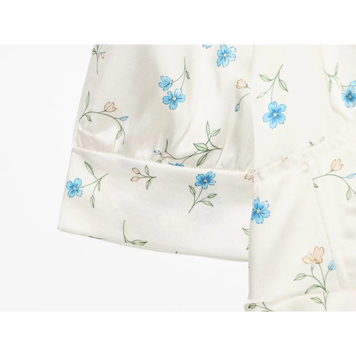 Close-up elbow sleeve cuff, folded hem, ditsy blue floral print on silky white fabric