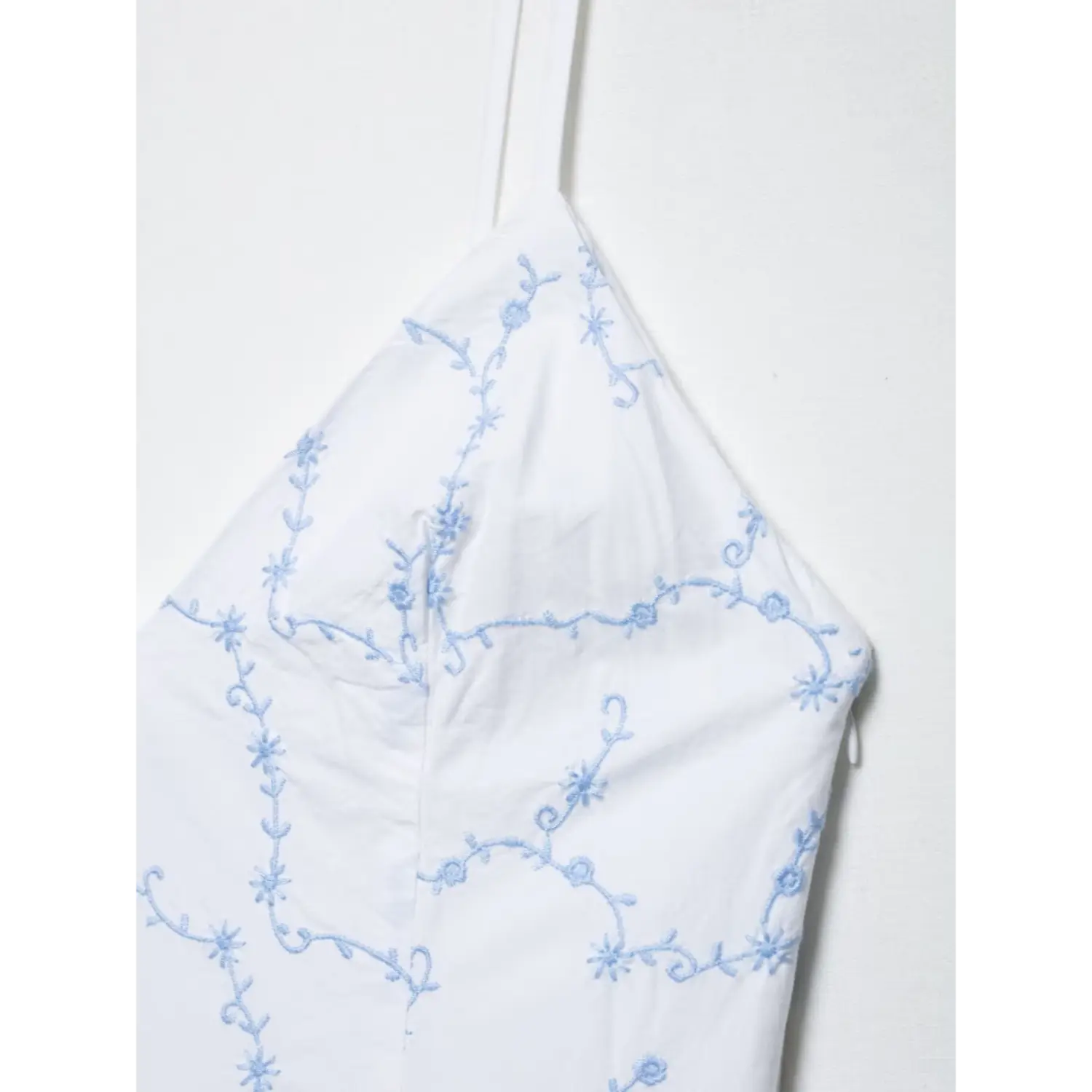 Close-up bust detail light blue vine flower embroidery on white spaghetti strap dress