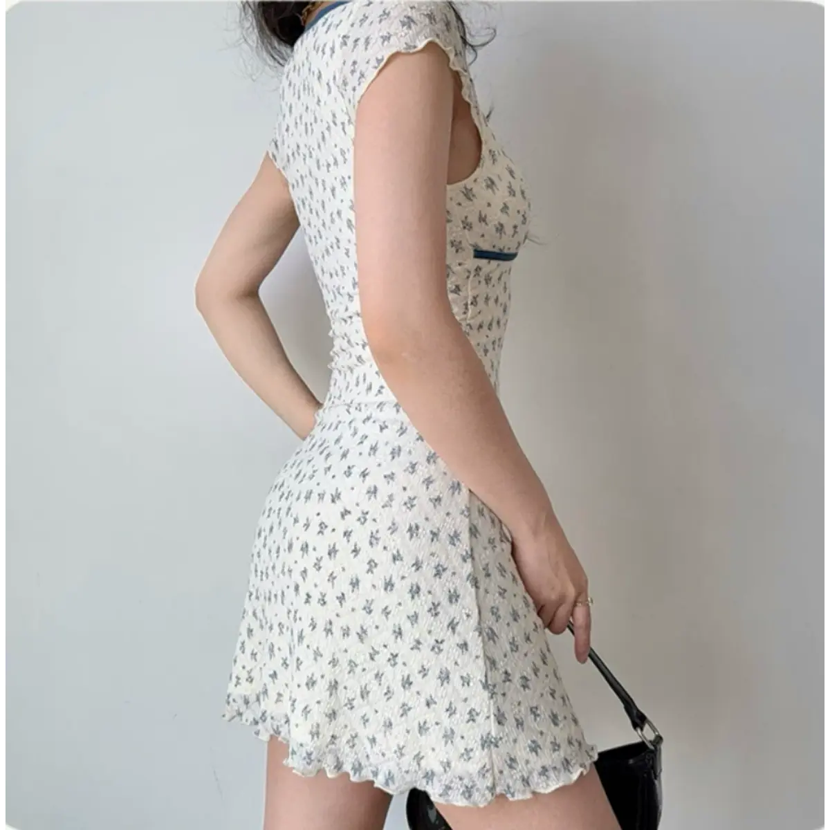 Back view of a white floral mini dress with blue accents and cap sleeves.