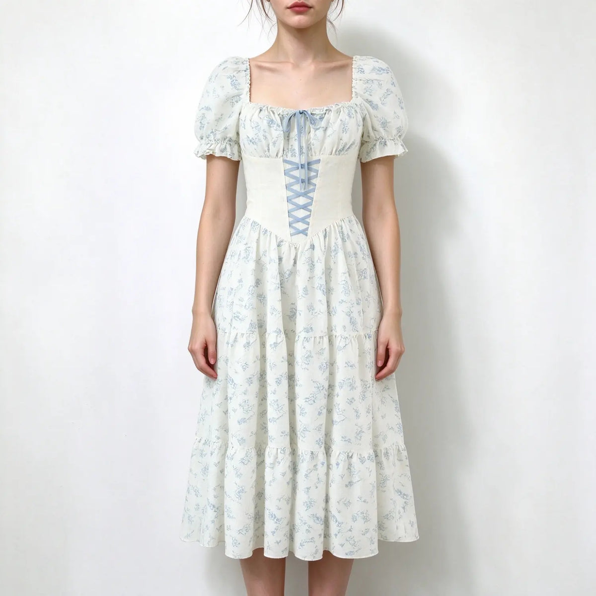 Model wearing white maxi dress with light blue floral print, square neck puff short sleeves, corset lace-up waist, tiered skirt