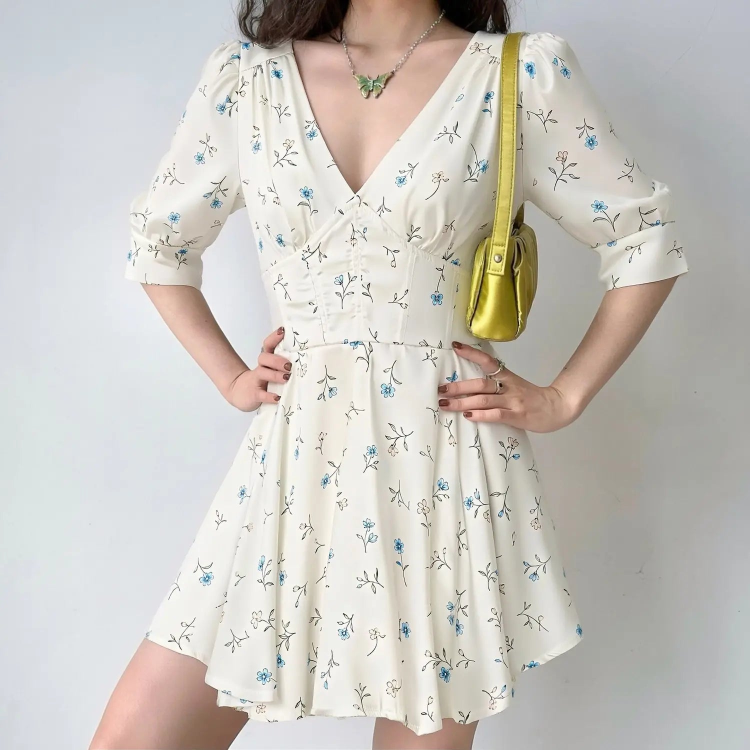 Woman model wearing white satin floral mini dress, deep V neck, puff elbow sleeves, corset waist, casual outfit studio shot
