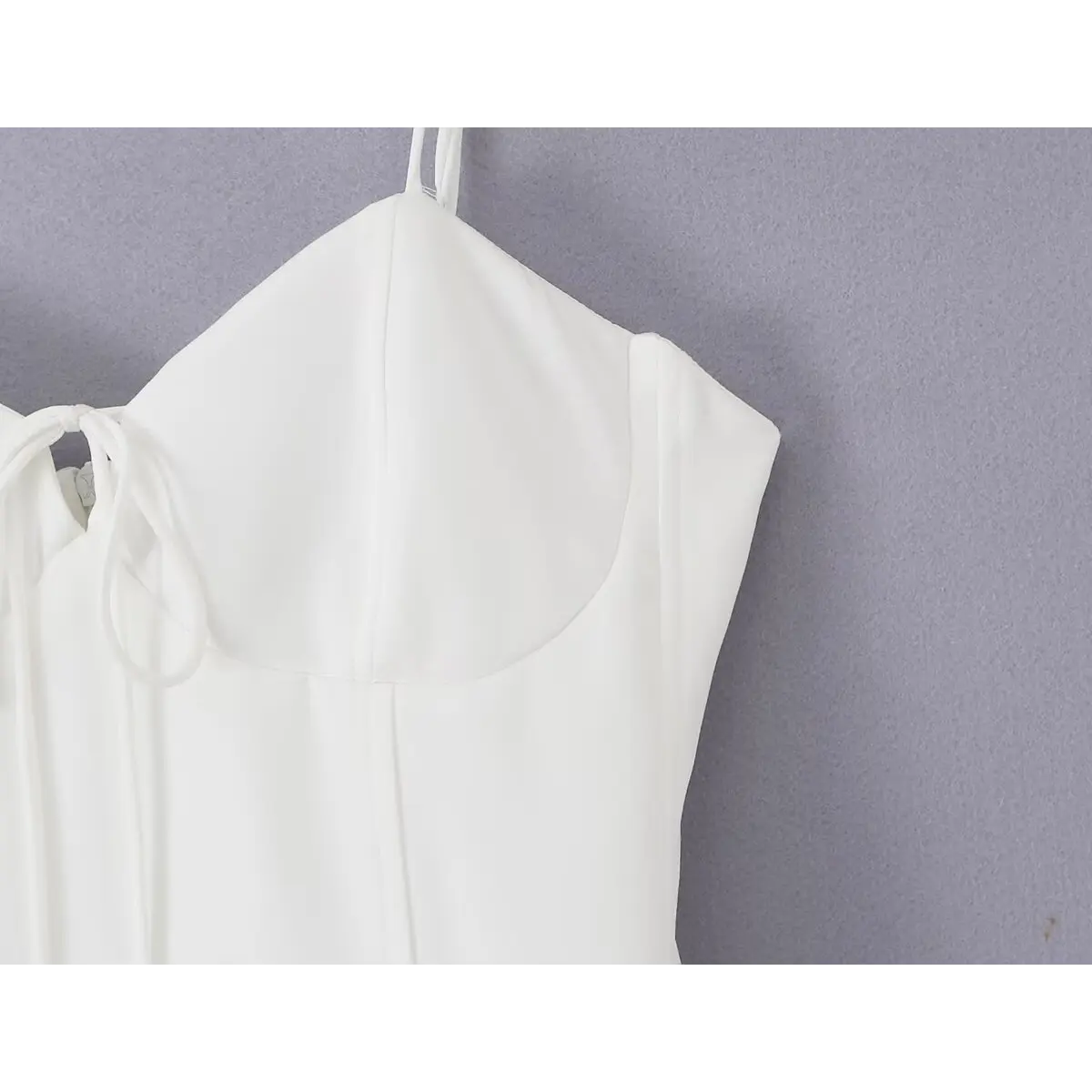 Close-up of the back neckline and adjustable spaghetti straps on the white cami dress
