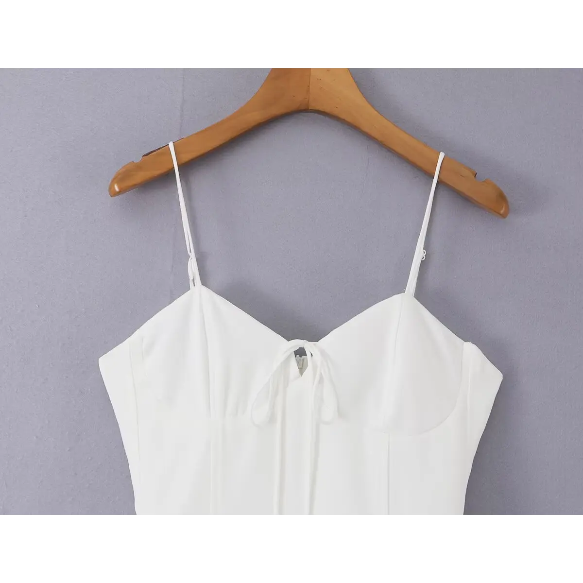 Close-up of the front bow and keyhole detail on the white cami dress