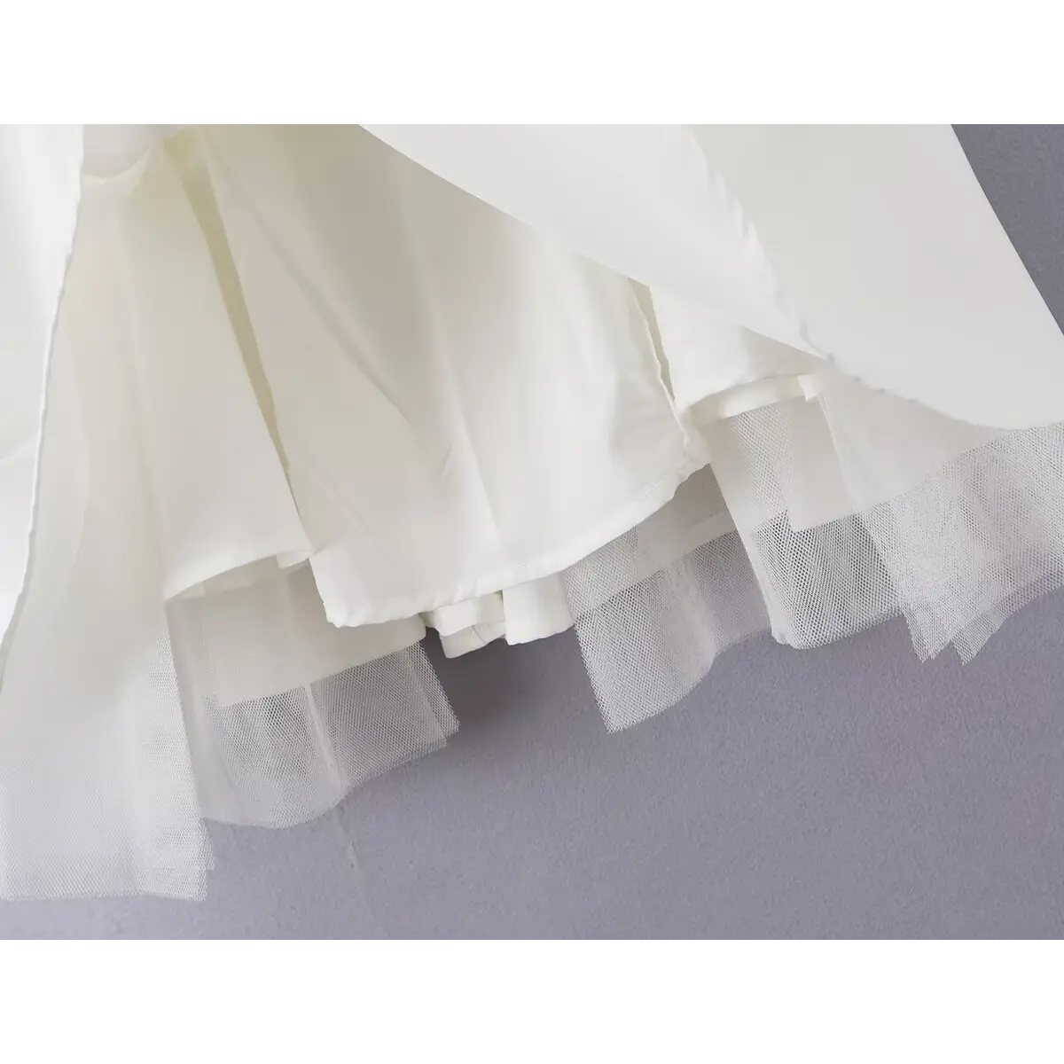 Close-up of the layered skirt construction and inner tulle on the white bow dress