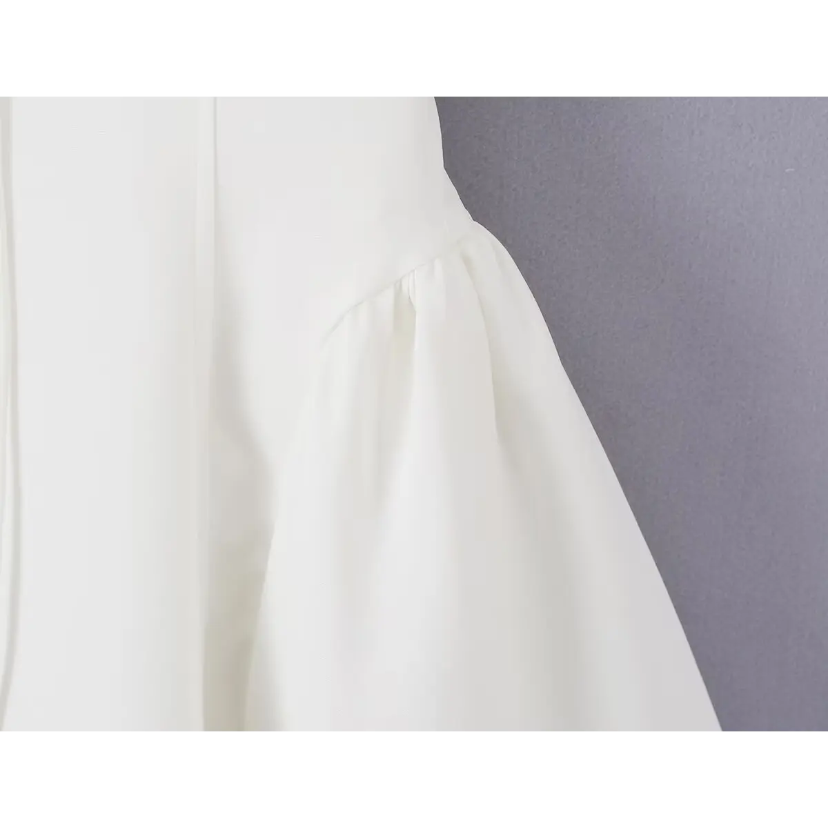Close-up of the waist seam where the bodice meets the flared skirt on the white bow dress