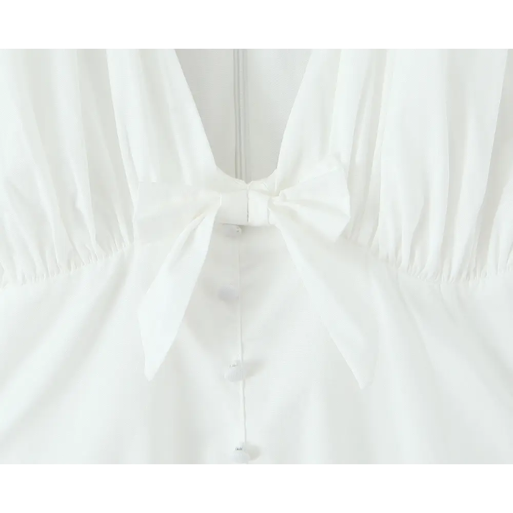 Close-up of self-tie bow at bust and decorative buttons