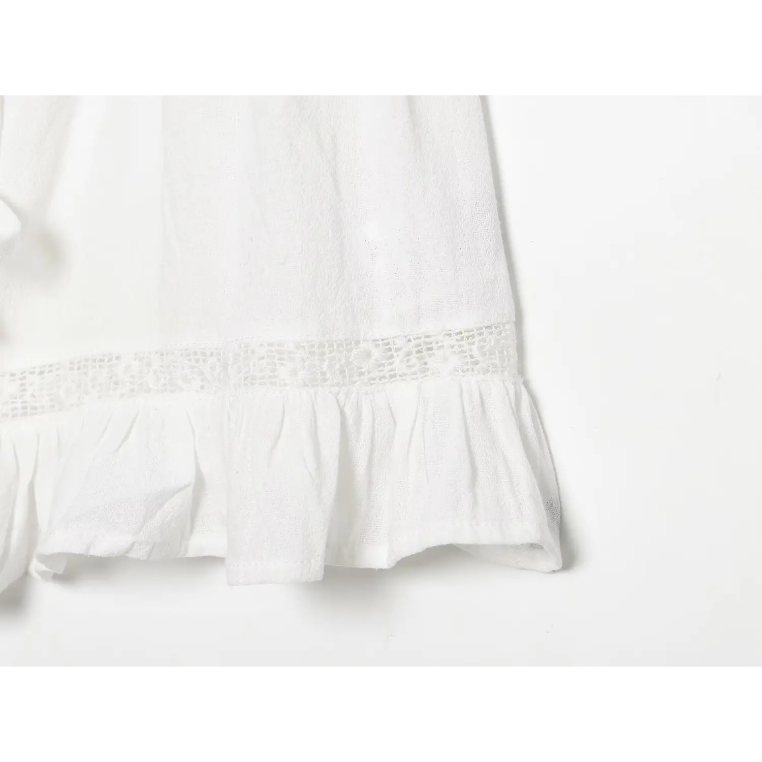 Bottom hem partial close-up, hollow mesh lace panel, gathered flowy ruffle hem, lightweight crinkled white fabric