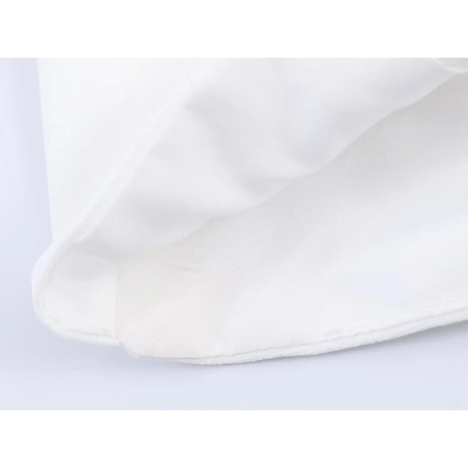 Close-up of inner lining fabric and bottom hem stitching on white cropped camisole