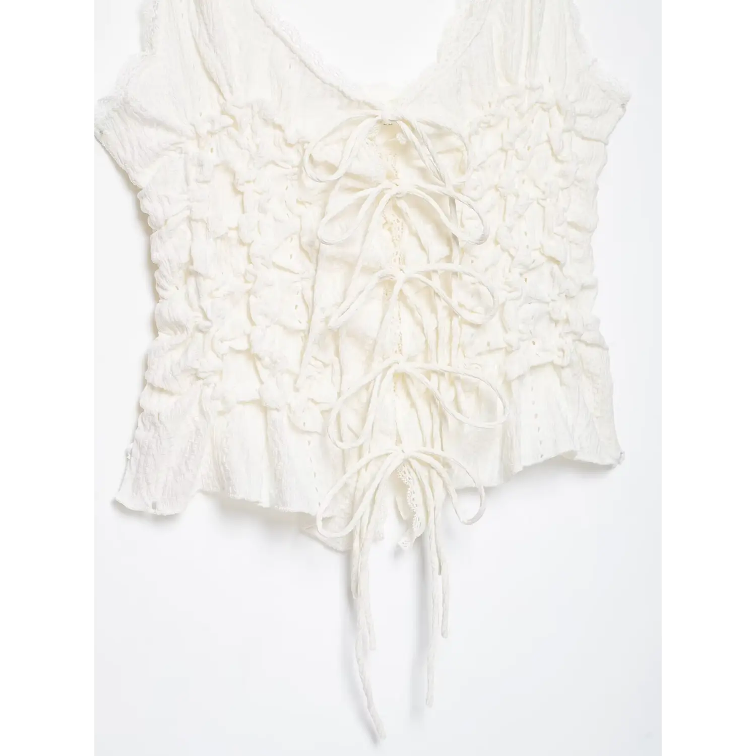 Close‑up of multi tie lace‑up back bodice on white crinkle cami top, textured ruched fabric, lace inset detail, white background