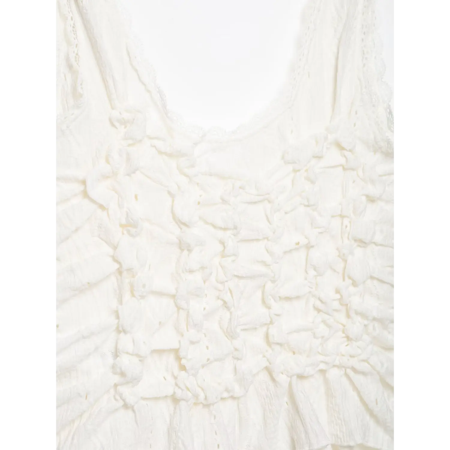 Close‑up front bodice of white cami top, dense ruched crinkle eyelet fabric texture, v‑neck with scallop lace trim, white background