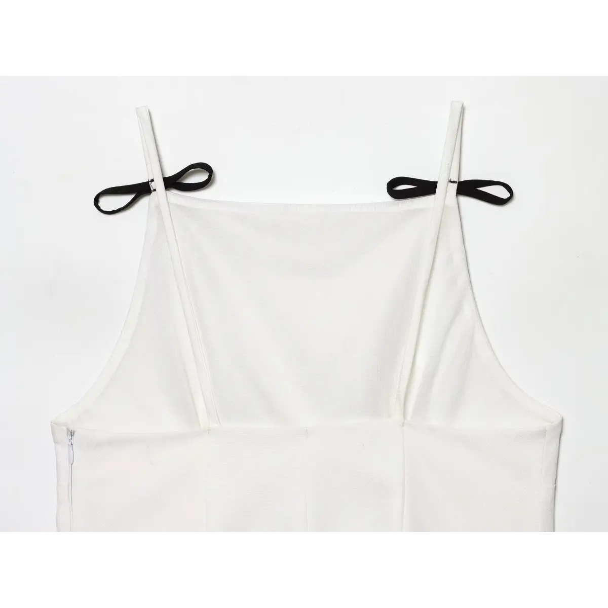 Close-up of the black bow details on the straps of the white square-neck camisole