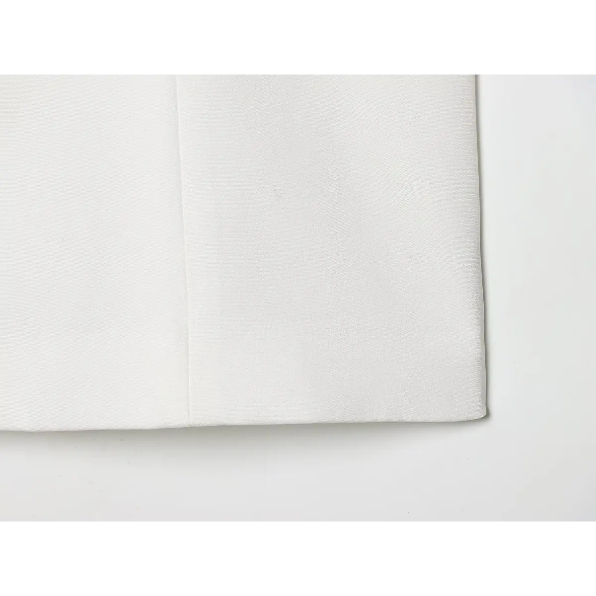 Close-up of the straight hem and seam stitching on the white camisole top