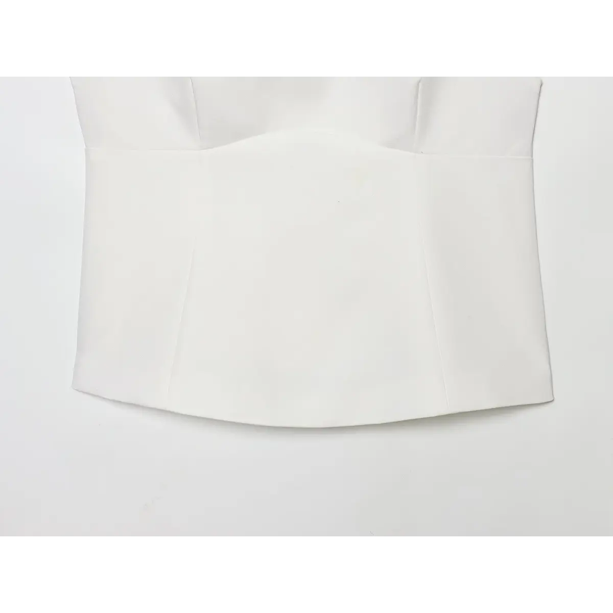 Partial view showing the bottom hem and vertical panel stitching on the white camisole