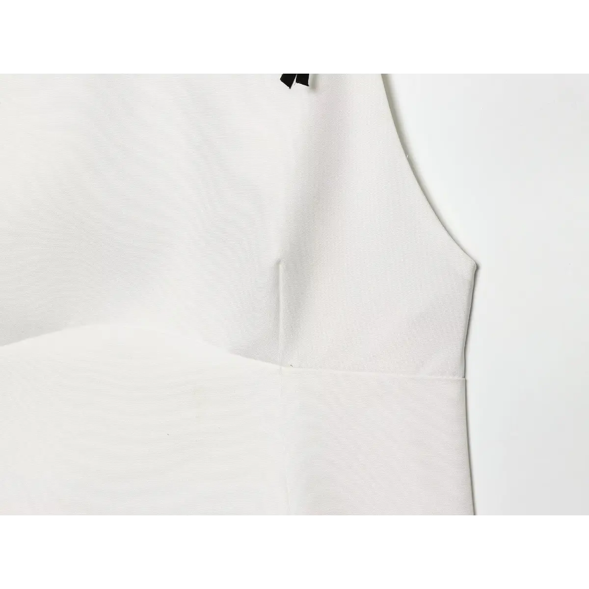 Close-up of the side seam and bust shaping on the white camisole top