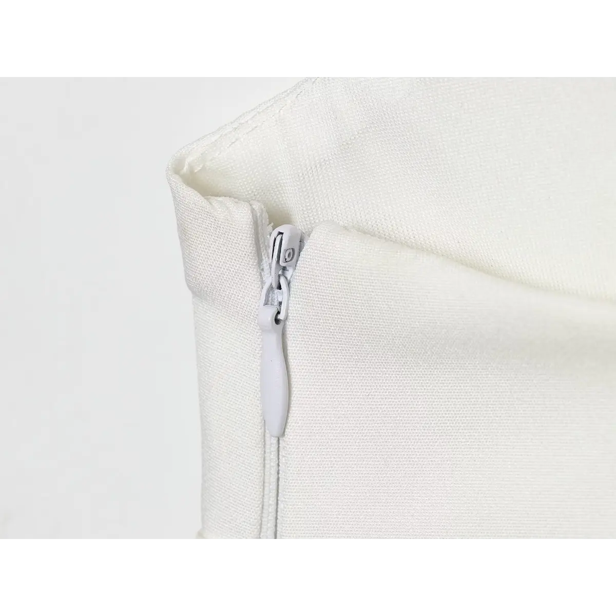 Close-up of the side zipper pull tab on the white camisole top