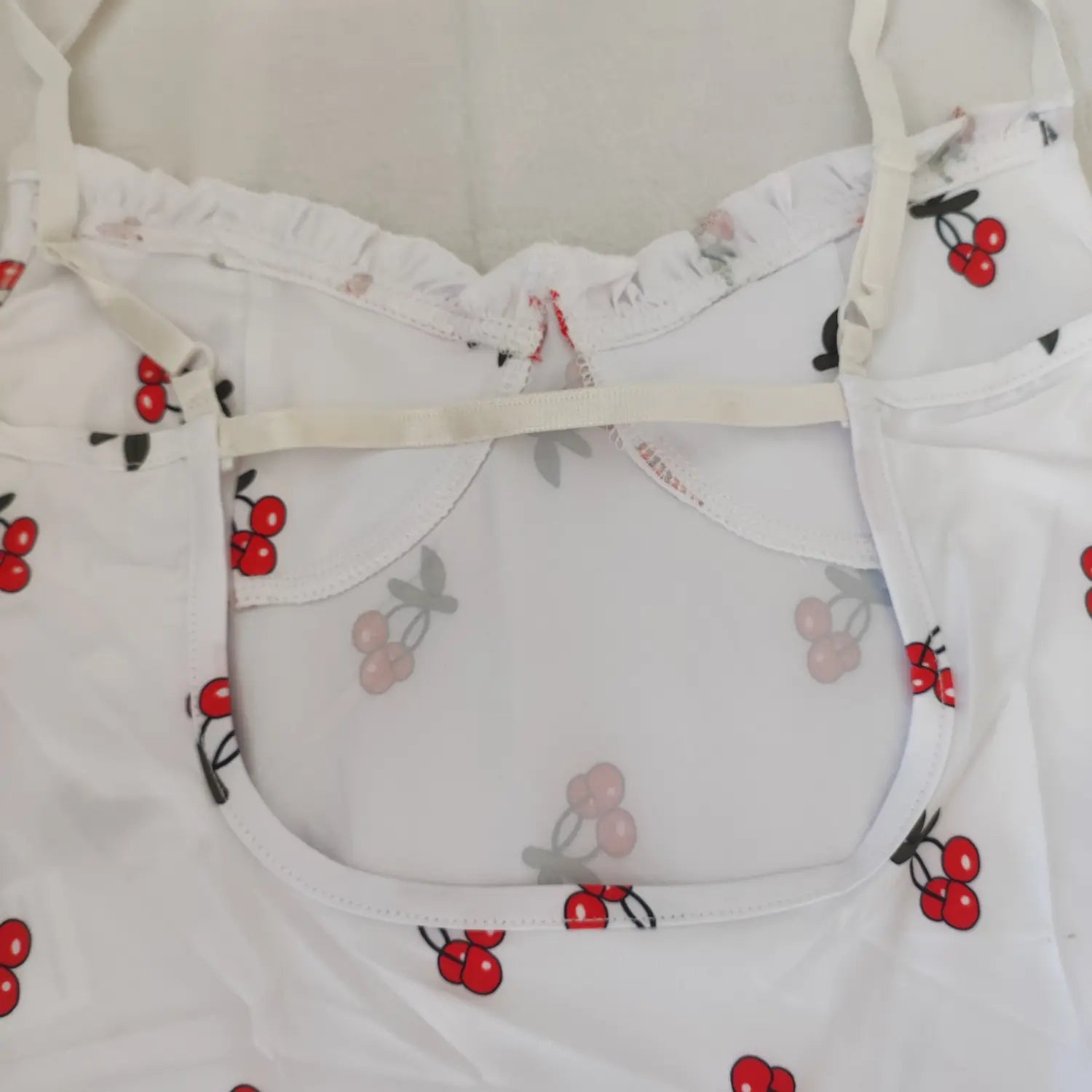 Close‑up back cut‑out panel and inner adjustable strap construction white cherry print bodysuit