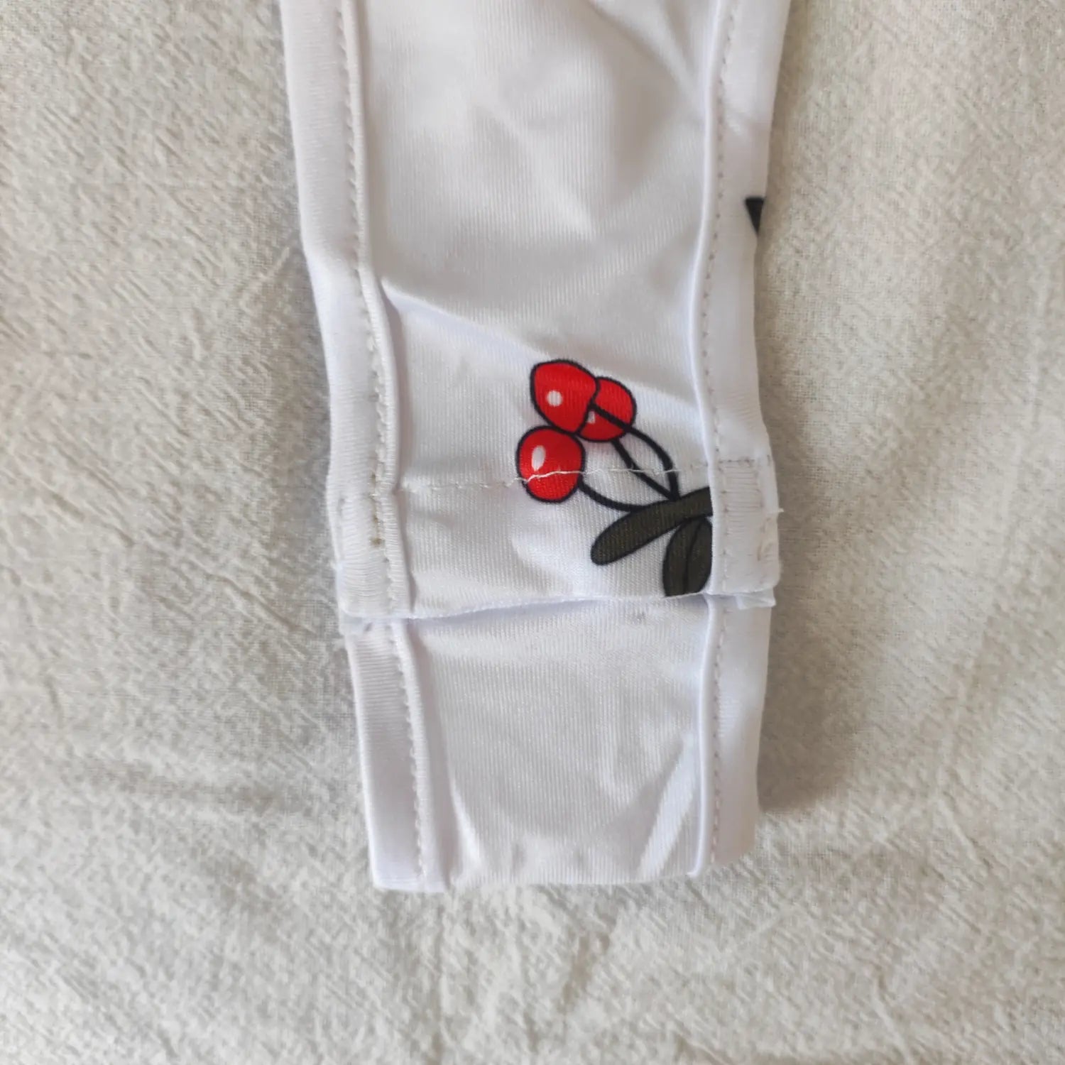 Close‑up crotch seam stitching detail white cherry print stretch bodysuit