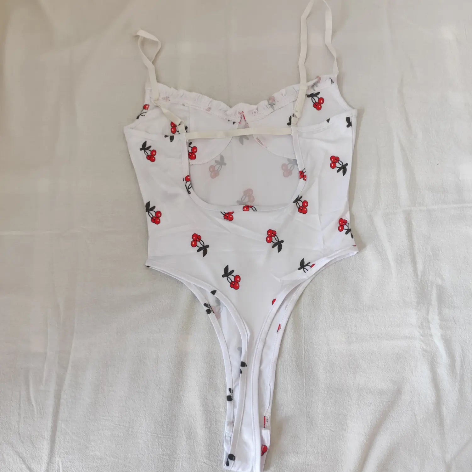 Flat lay full back view white cherry print bodysuit cut‑out back and adjustable spaghetti straps