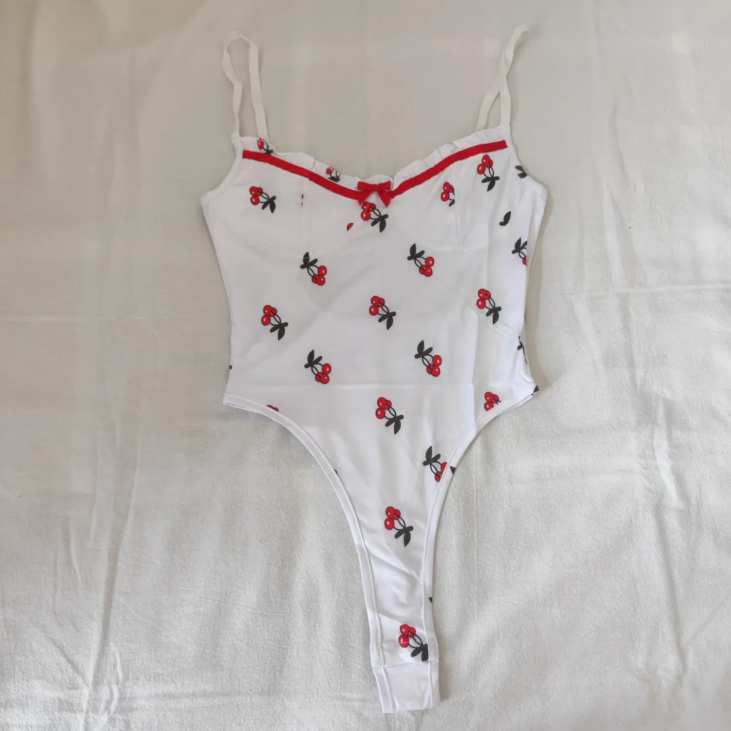 Flat lay full front view white cherry print bodysuit sweetheart neckline red bow and ruffle trim