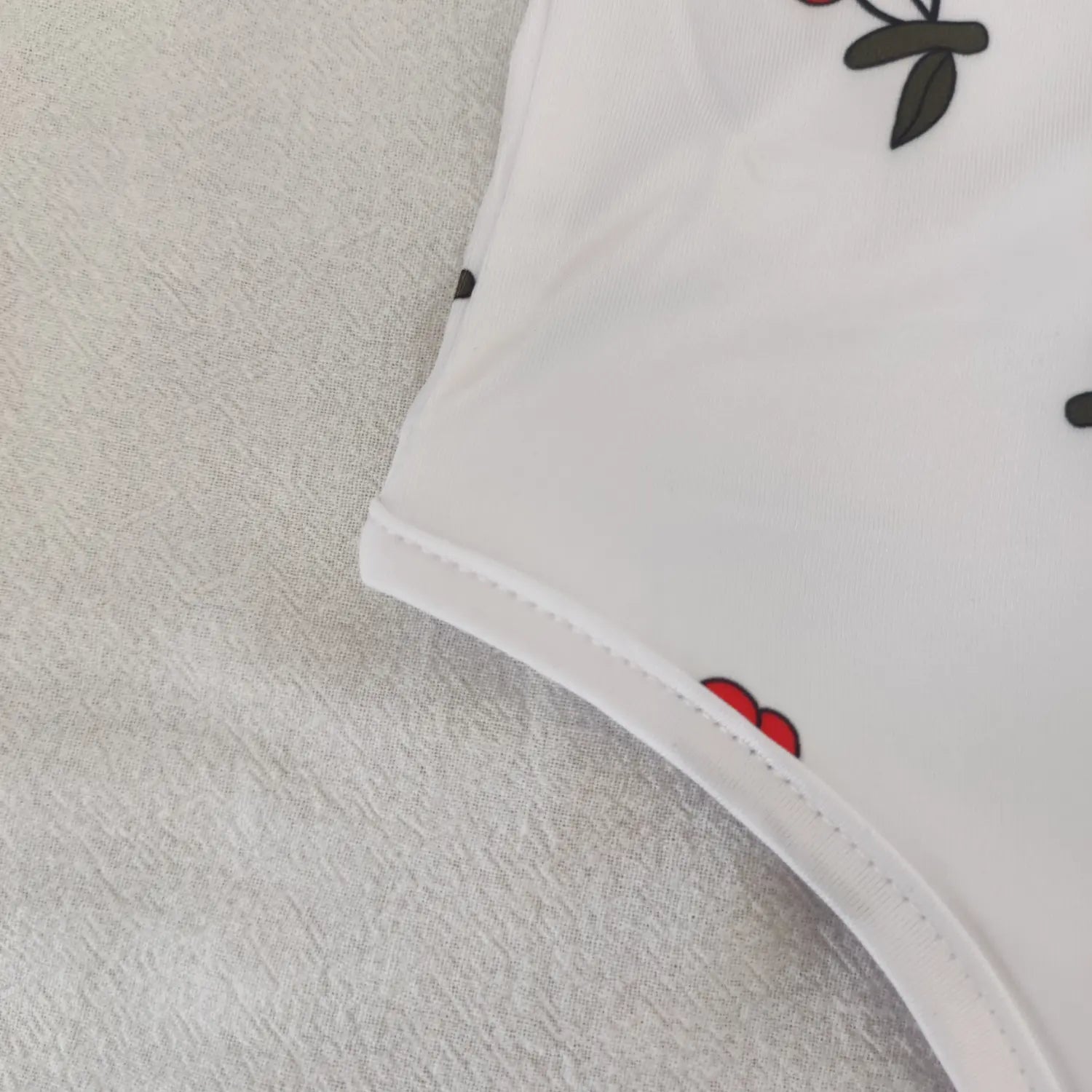 Close‑up side hem neat stitching detail white cherry print stretch bodysuit