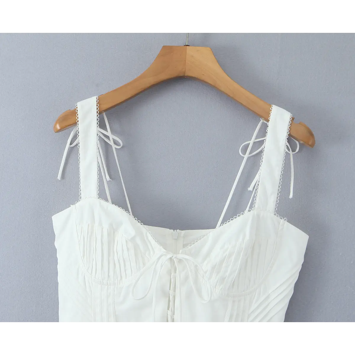 Close-up of the neckline, strap ties, and lace-up bust detail on the white corset dress.