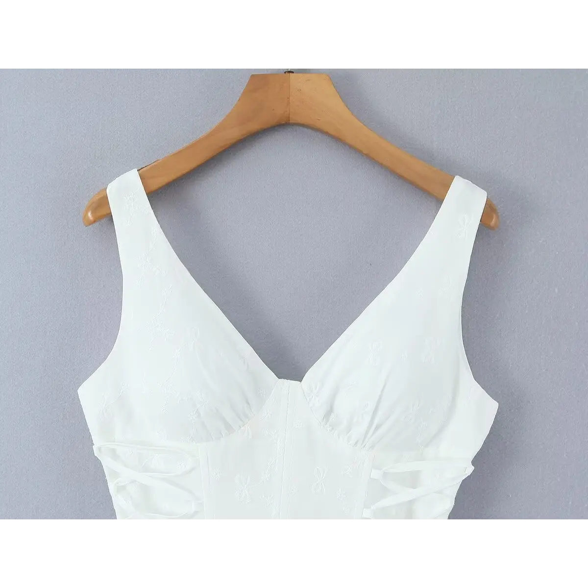 Close-up of the V-neckline and wide cami straps on the white corset-style dress