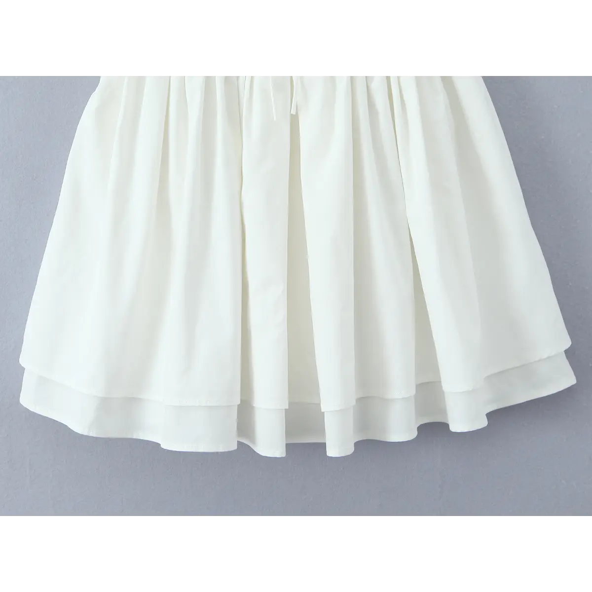 Close-up of the double-layered skirt hem and fabric texture on the white corset dress