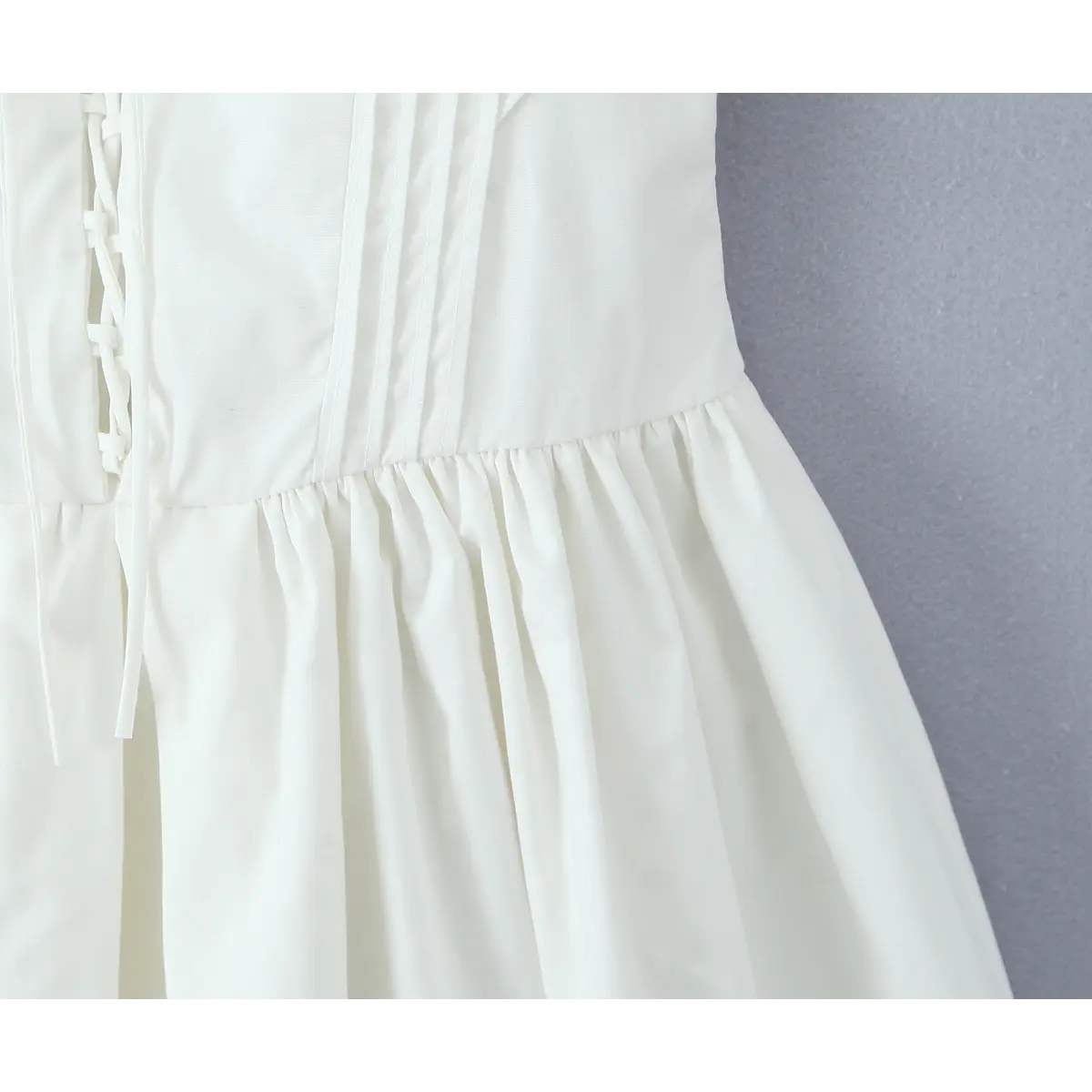 Close-up of the waist corsetry and gathered skirt transition on the white dress.