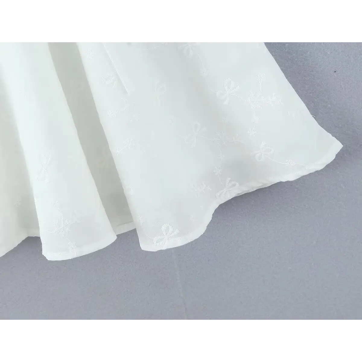 Close-up of the flowy skirt hem and lightweight fabric texture on the white corset dress
