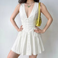 Model wearing white sleeveless corset mini dress, v neck lace trim, side drawstring, flare skirt