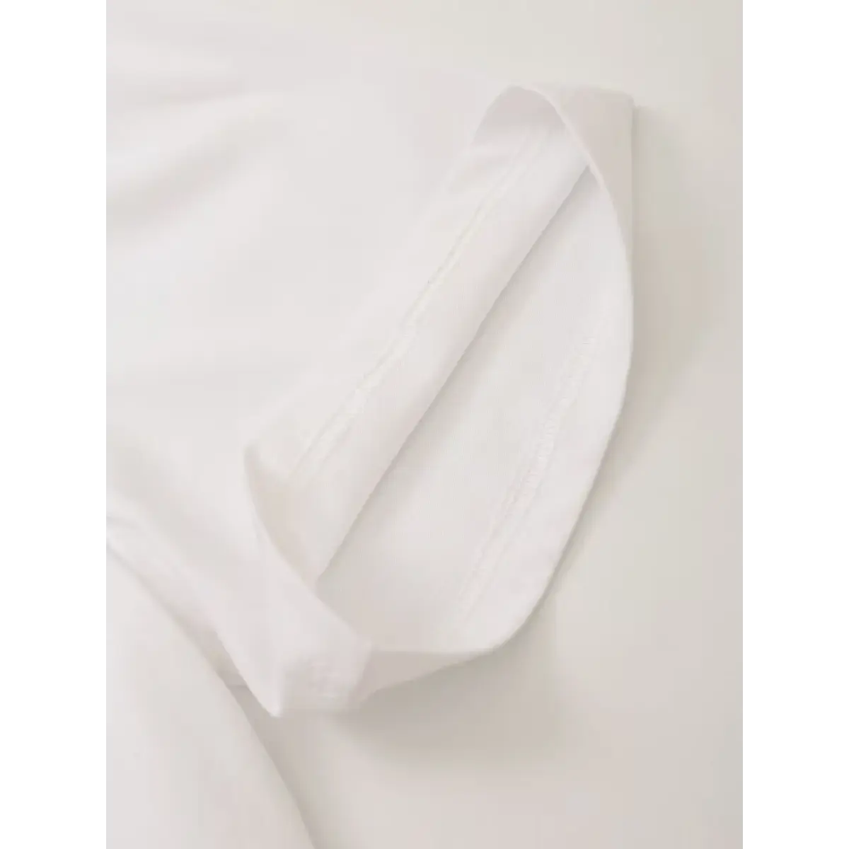 Close of double-stitched sleeve cuff on white cotton photo graphic casual tee