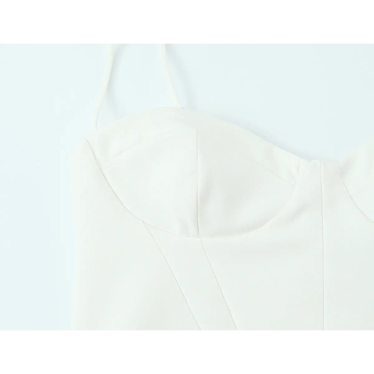 Close-up of the bodice on the white crepe cami dress, showing the structured bustier cups, vertical seams, and thin spaghetti straps