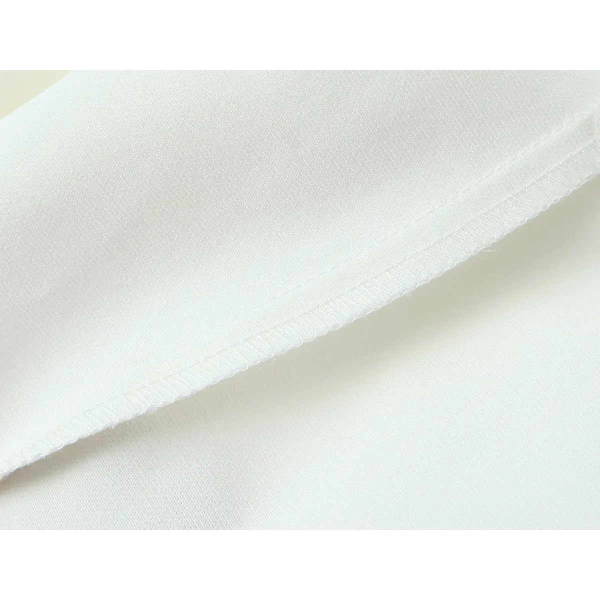 Close-up of the crepe fabric, showing the clean overlocked hem and smooth texture