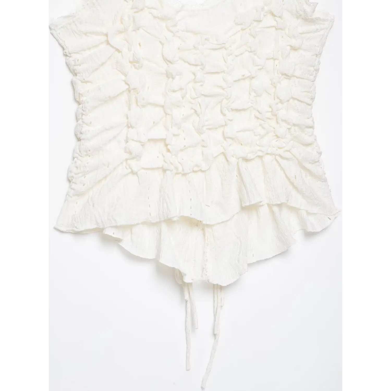 Flat‑lay full bottom view of white camisole top, layered peplum ruffle hem, hanging drawstring ties, ruched crinkle eyelet fabric, white background