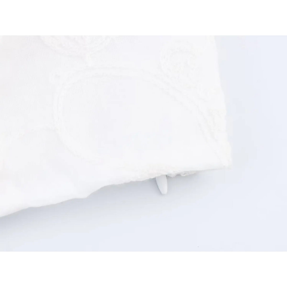 Close-up of bottom hem and invisible zipper on white paisley embroidered cropped top