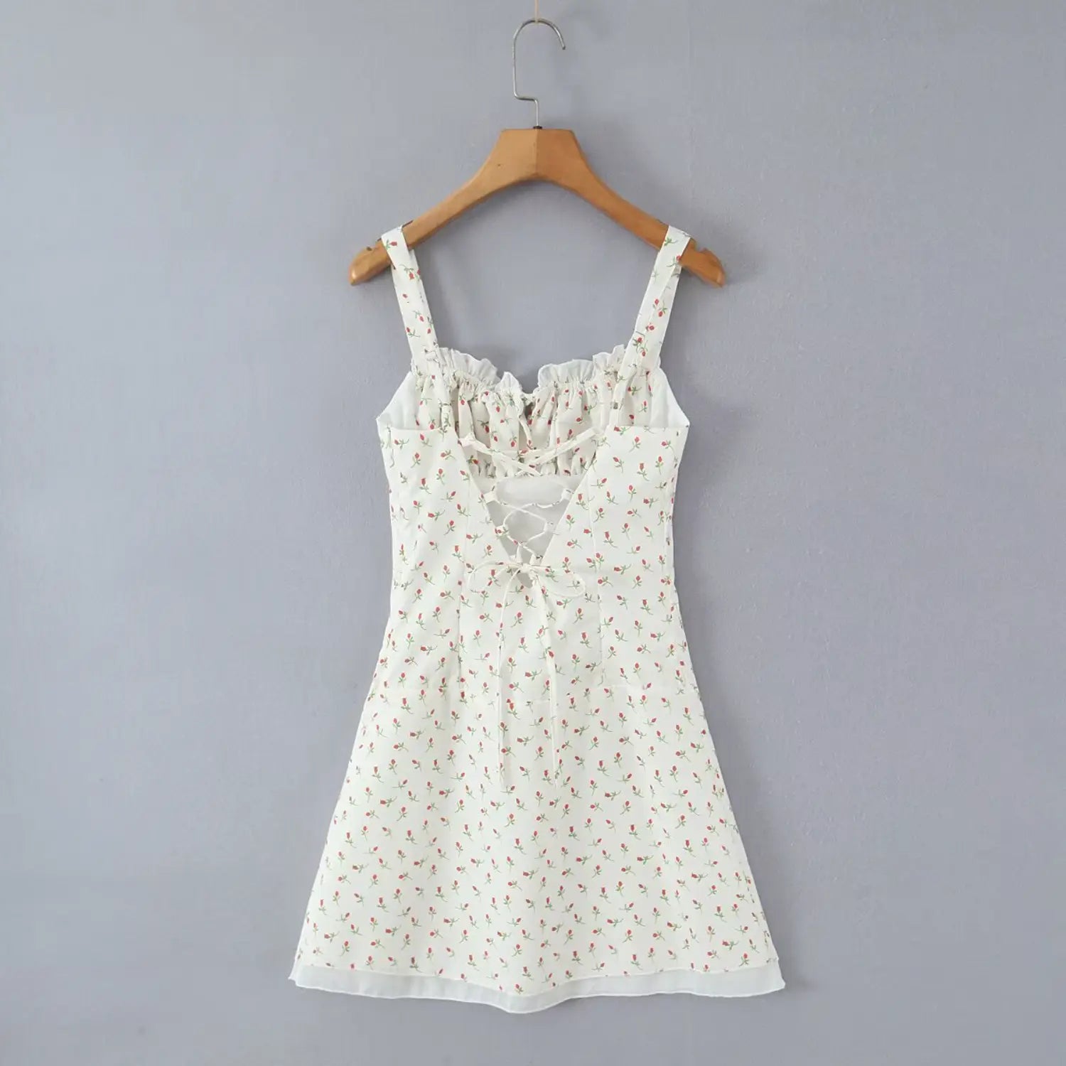 Full back hanging shot on wooden hanger display lace‑up tie‑back structure open back white rose print mini dress