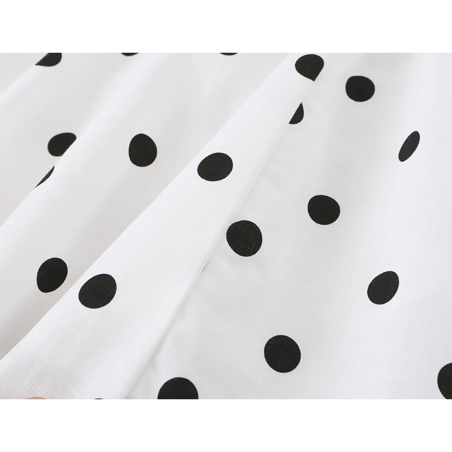 White black polka dot woven fabric macro flat shot, soft drape textile evenly printed big dot natural wrinkle texture white background detail