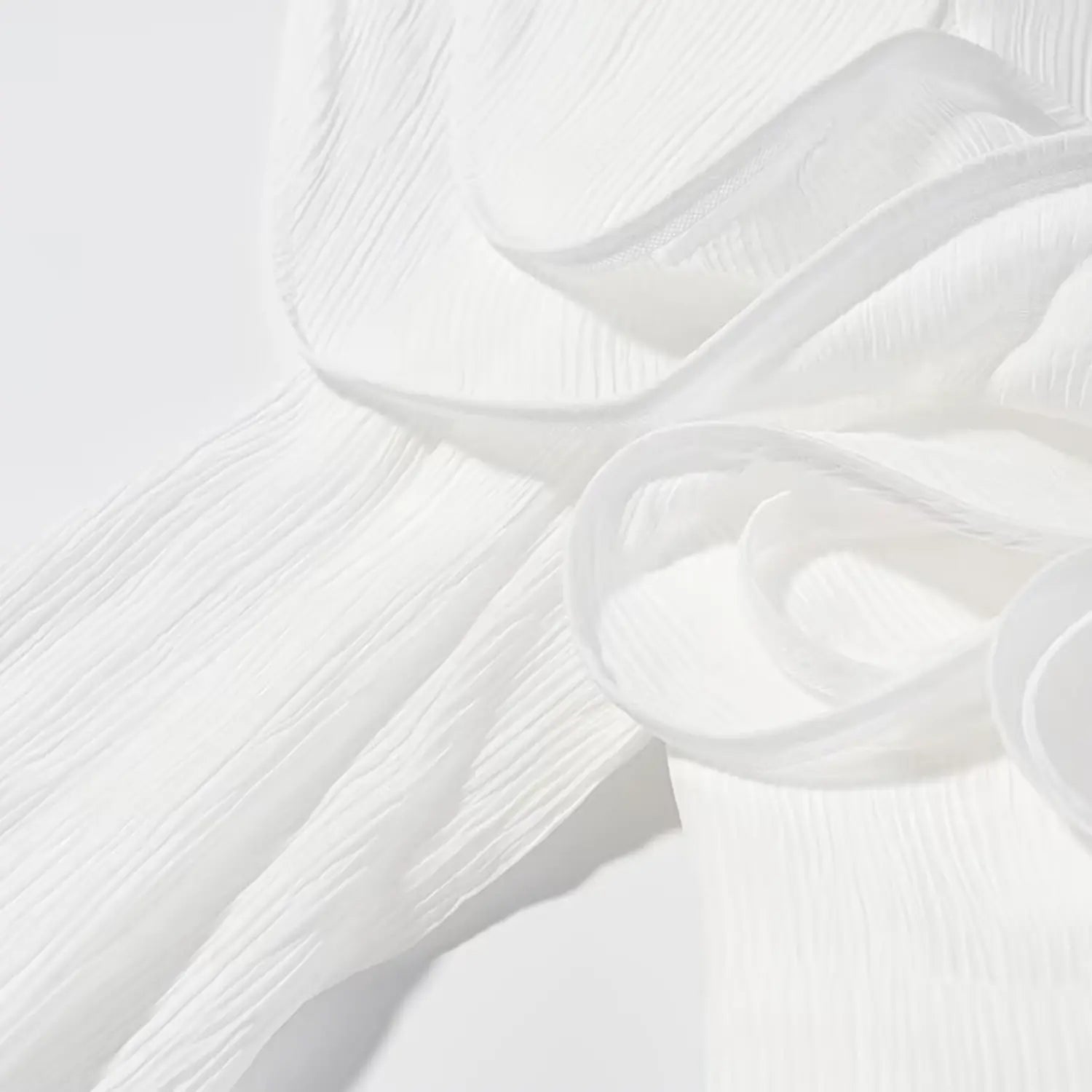 Close-up view of 3D floral applique alongside long sleeve crinkle texture fabric