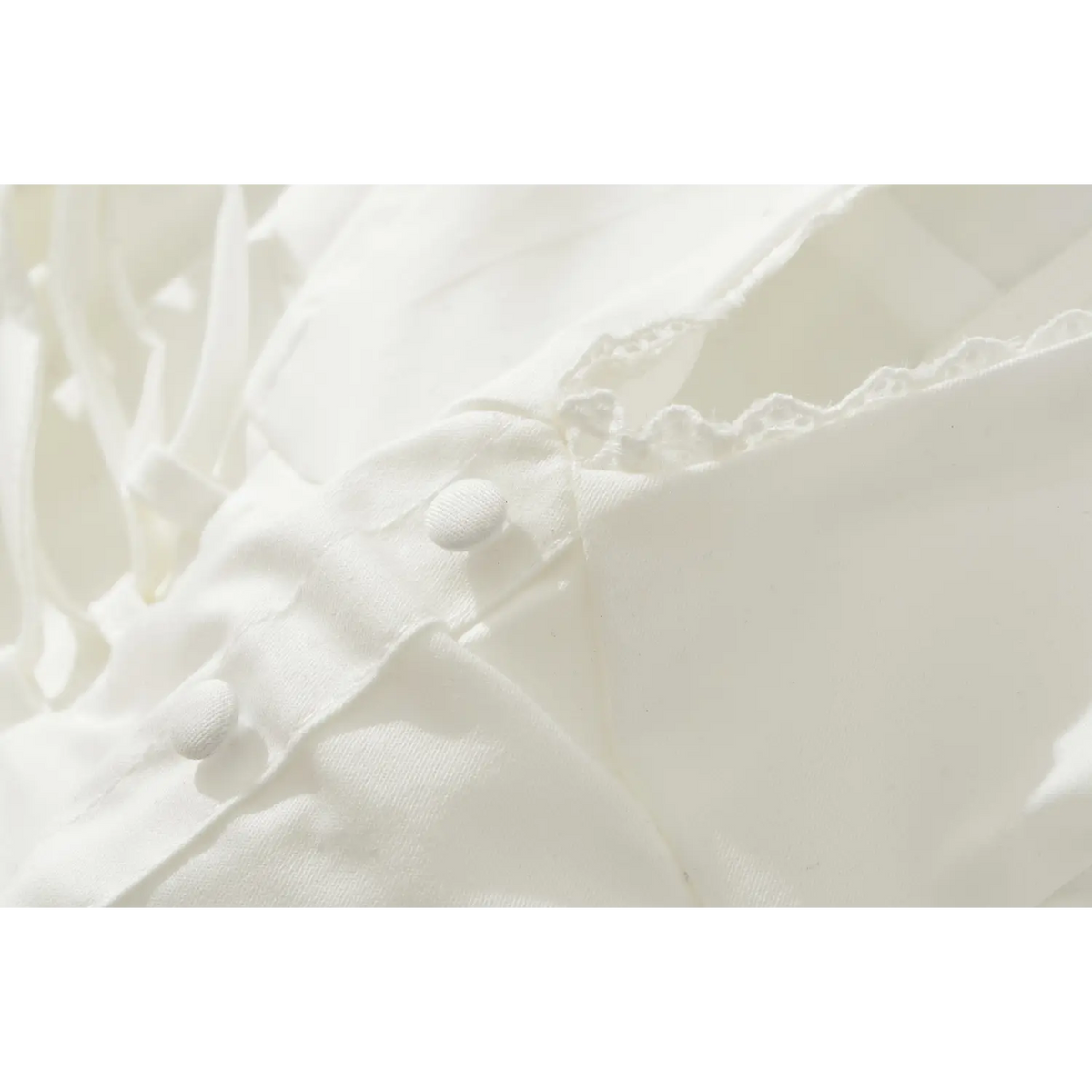 Close-up of fabric covered buttons and woven fabric texture on white corset mini dress