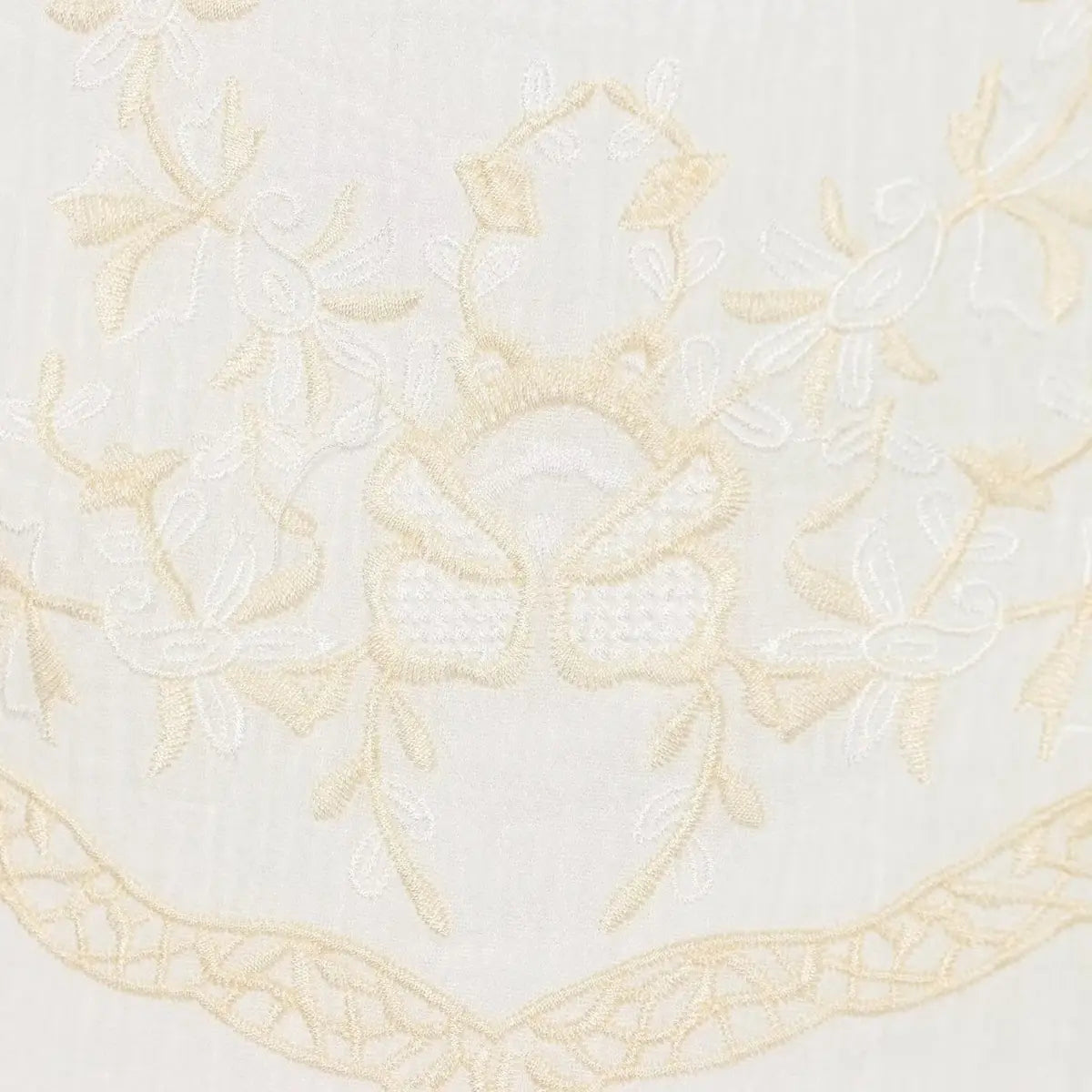 Macro view of the floral embroidery on white dress, showing detailed beige threadwork and decorative pattern.