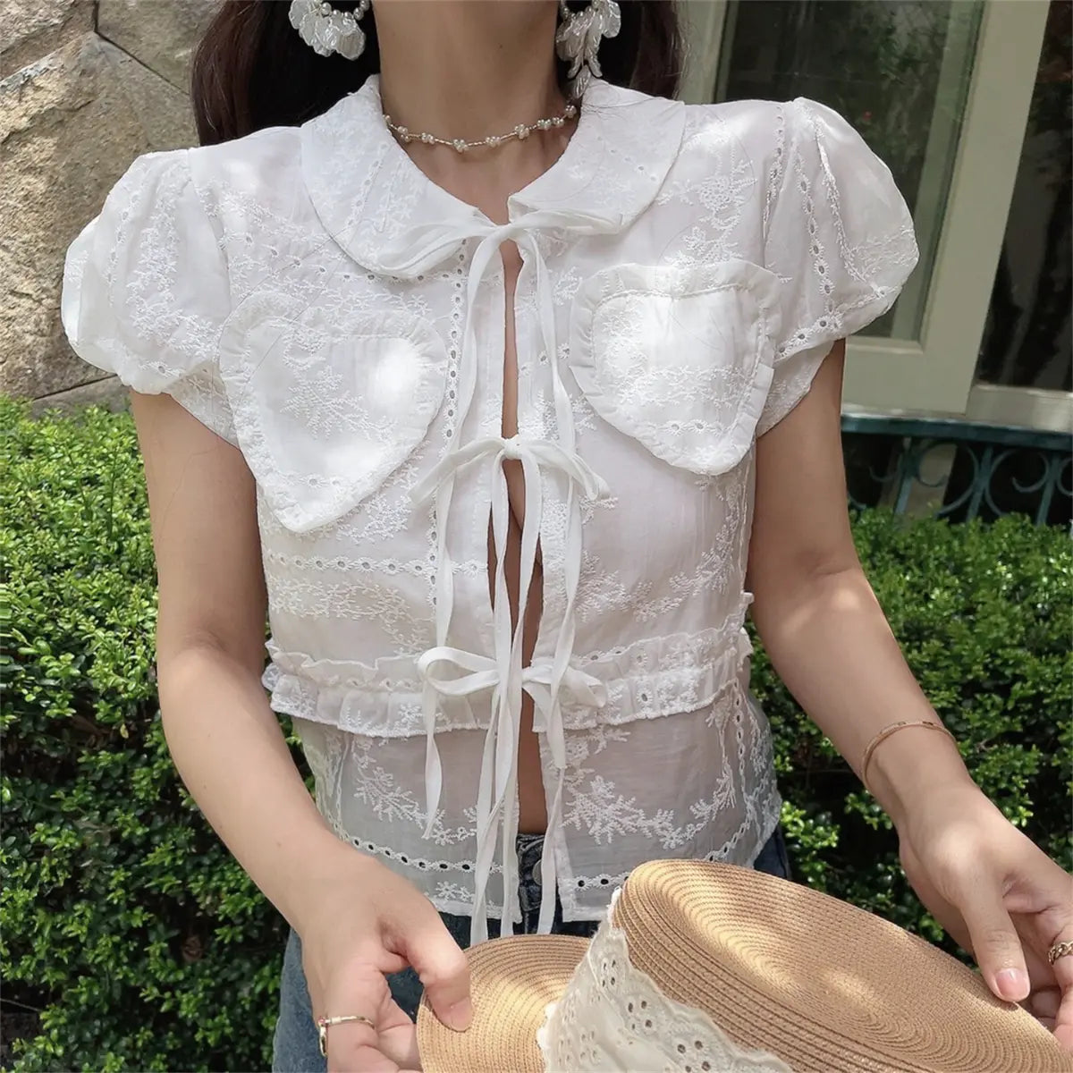 Close-up of the white embroidered blouse, showing the heart-shaped pockets and lace-up front.
