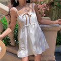 Full front view of a model in a white embroidered cami dress, showing the floral embroidery, gathered skirt, and ruffled hem.