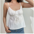 Close-up lifestyle shot of model in white textured cami top with adjustable straps