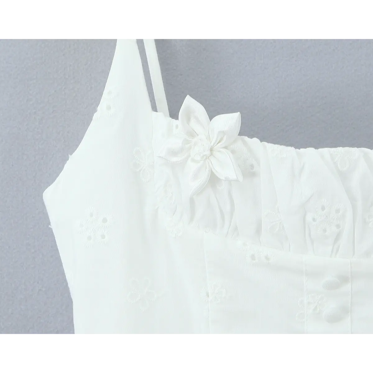 Close-up of the satin flower appliqué, gathered bust, and thin spaghetti straps.