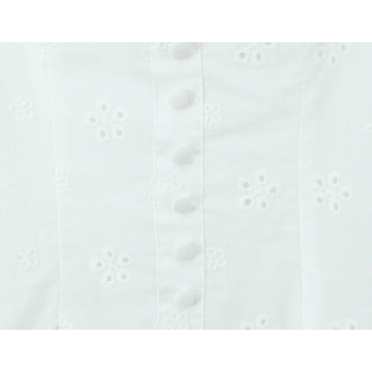 Close-up of the fabric-covered buttons and matching floral embroidery on the bodice.
